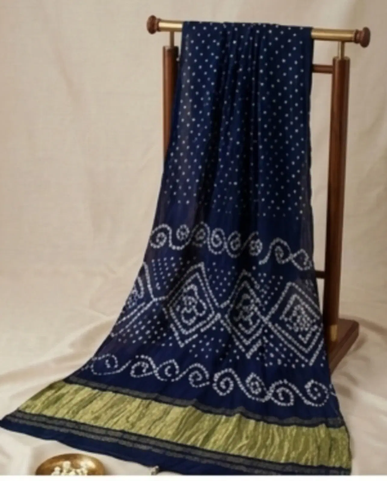 Navy blue printed saree with white dotted motifs and decorative border draped on a wooden stand