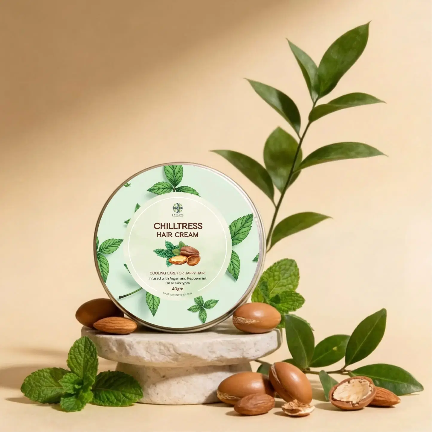 Satliva Chilltress Hair Cream tin with mint leaves and argan nuts on a beige background