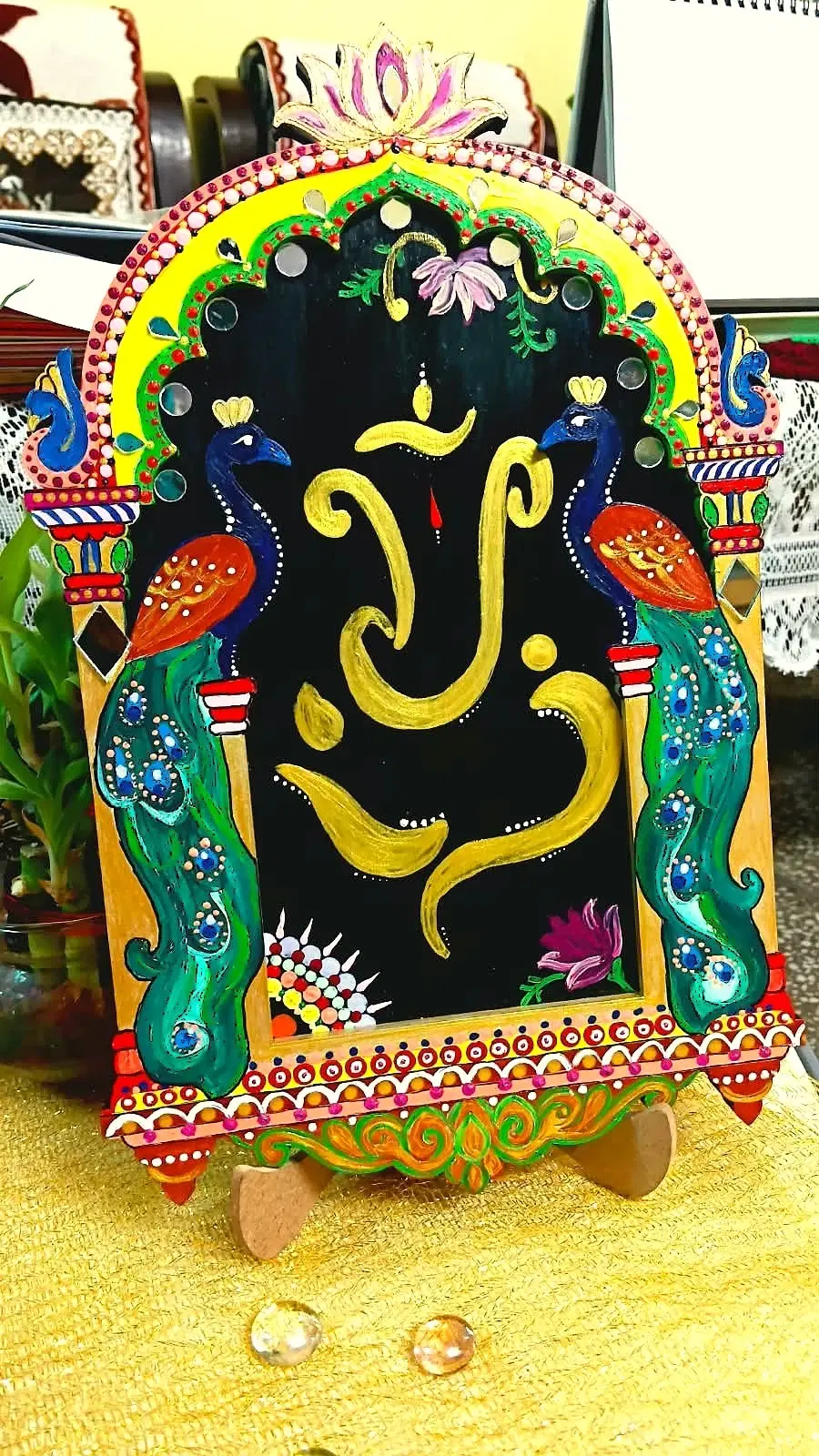 Hand-painted wooden Lord Ganesha plaque with peacock motifs on a small display stand