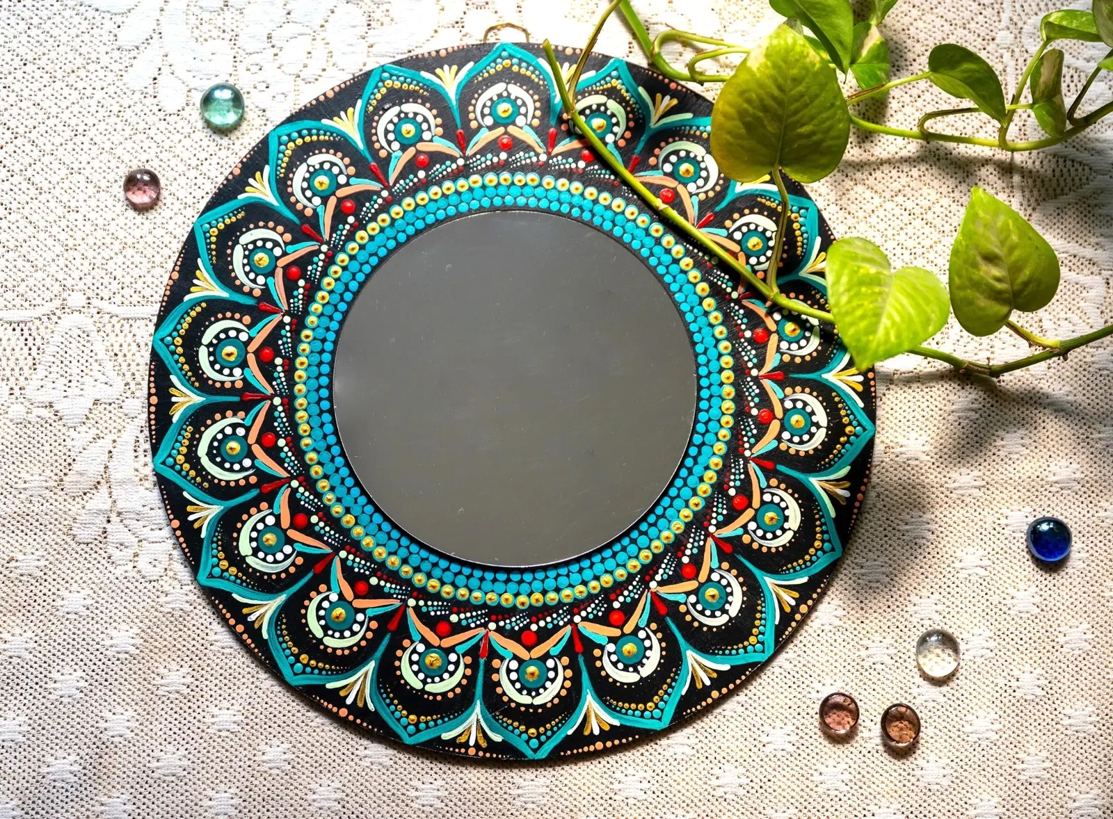 Round black wall mirror with colorful hand-painted mandala border on lace cloth with green vine leaves