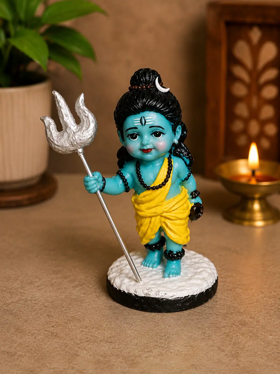 Blue baby Shiva idol figurine holding a trishul, wearing yellow drape on a round base
