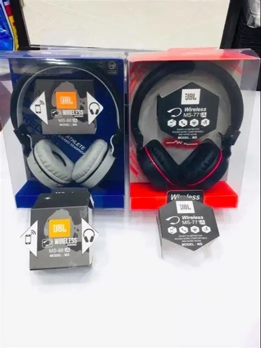 Two boxed JBL wireless over-ear headphones in blue-gray and black-red with product tags displayed in front