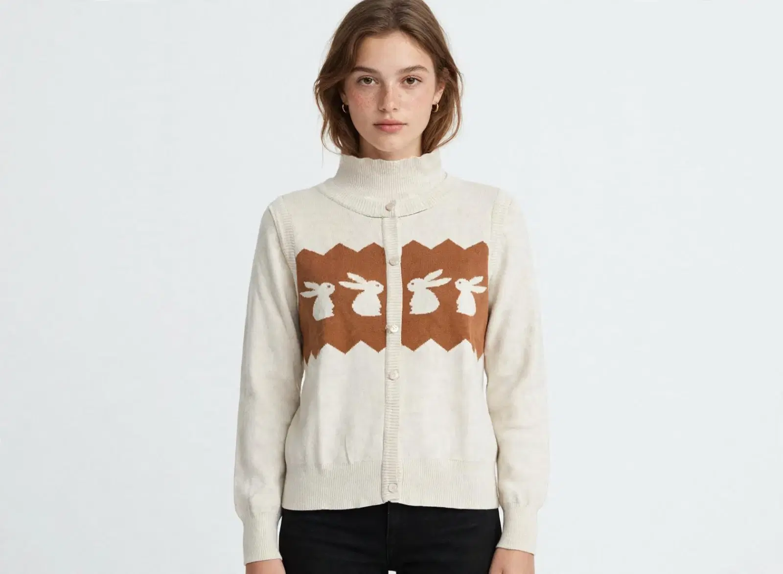Woman wearing a cream knit turtleneck cardigan with brown rabbit pattern and front buttons