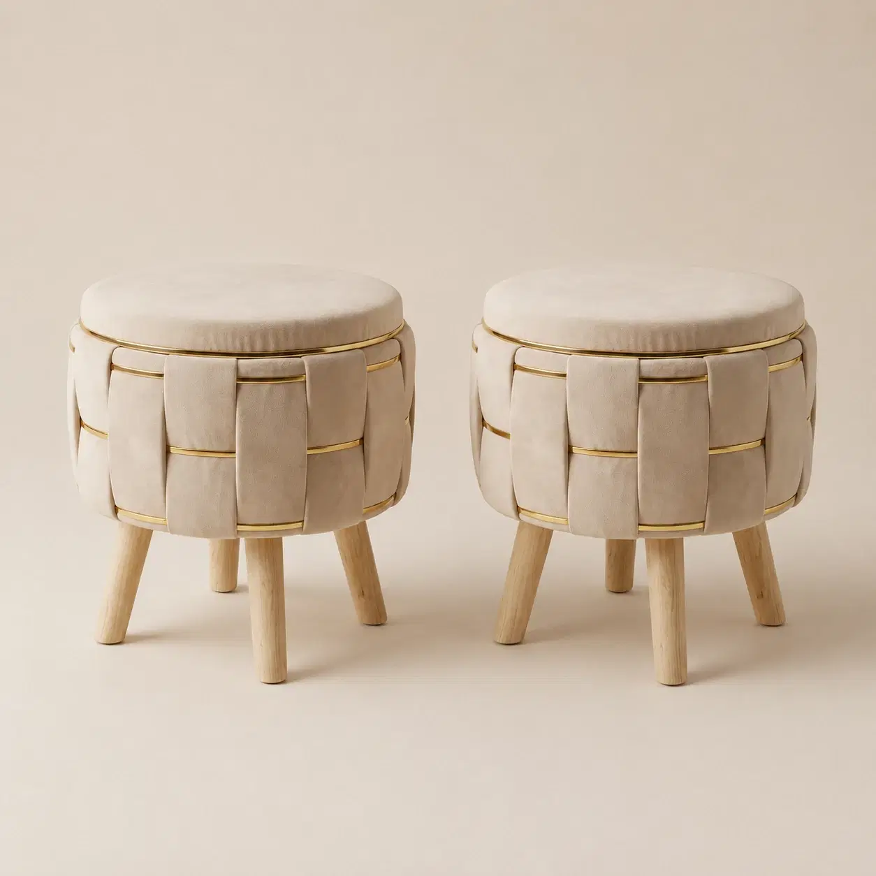 Two beige round velvet storage ottoman stools with gold accents and wooden legs