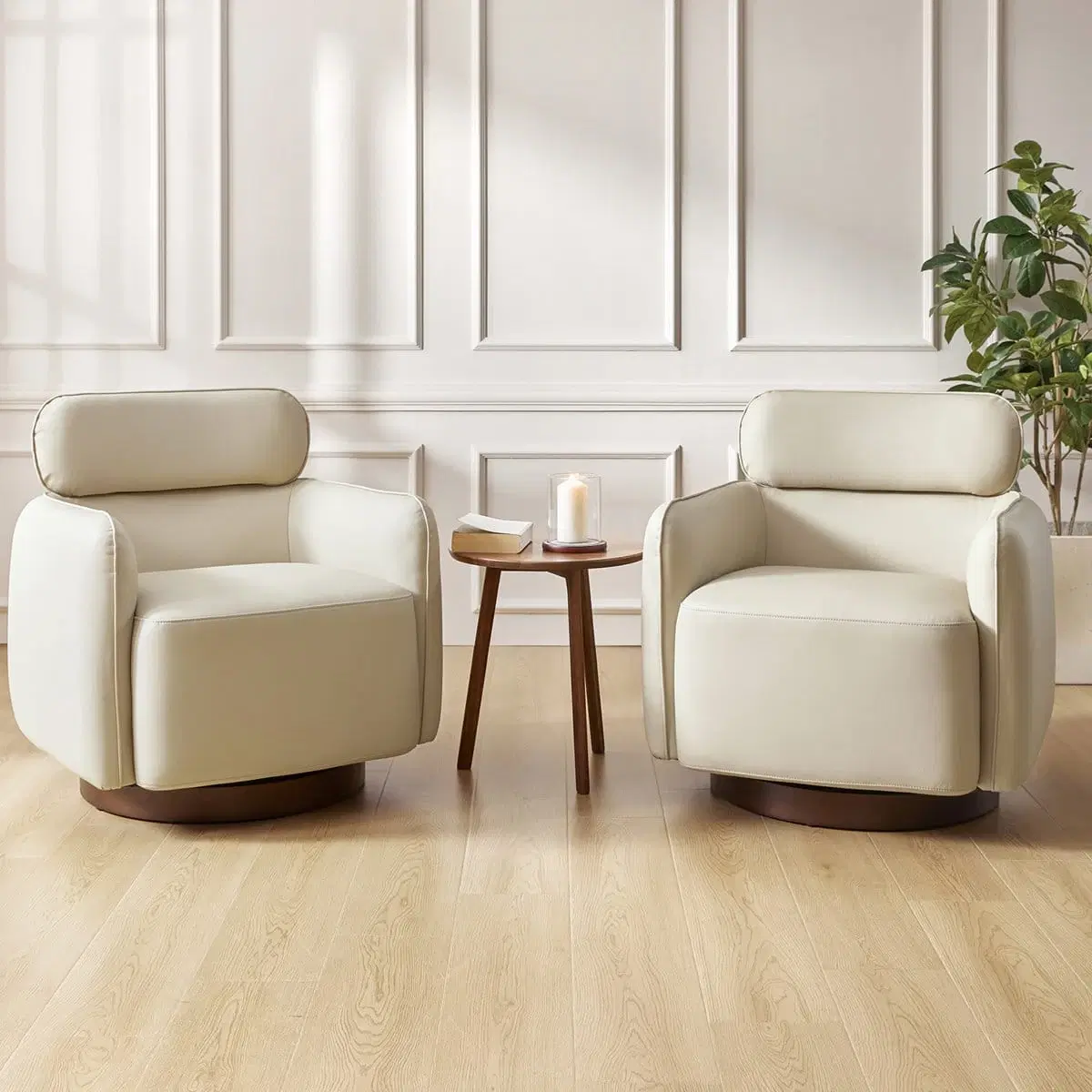 Two cream upholstered swivel accent chairs with rounded backs and dark wood bases in a staged living room