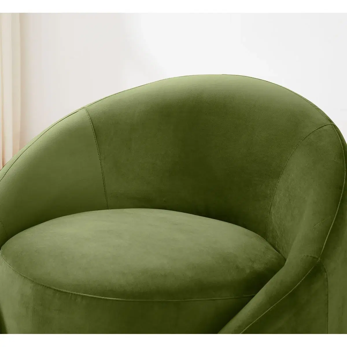 Close-up of the green velvet chair seat and curved barrel back with stitched side panels