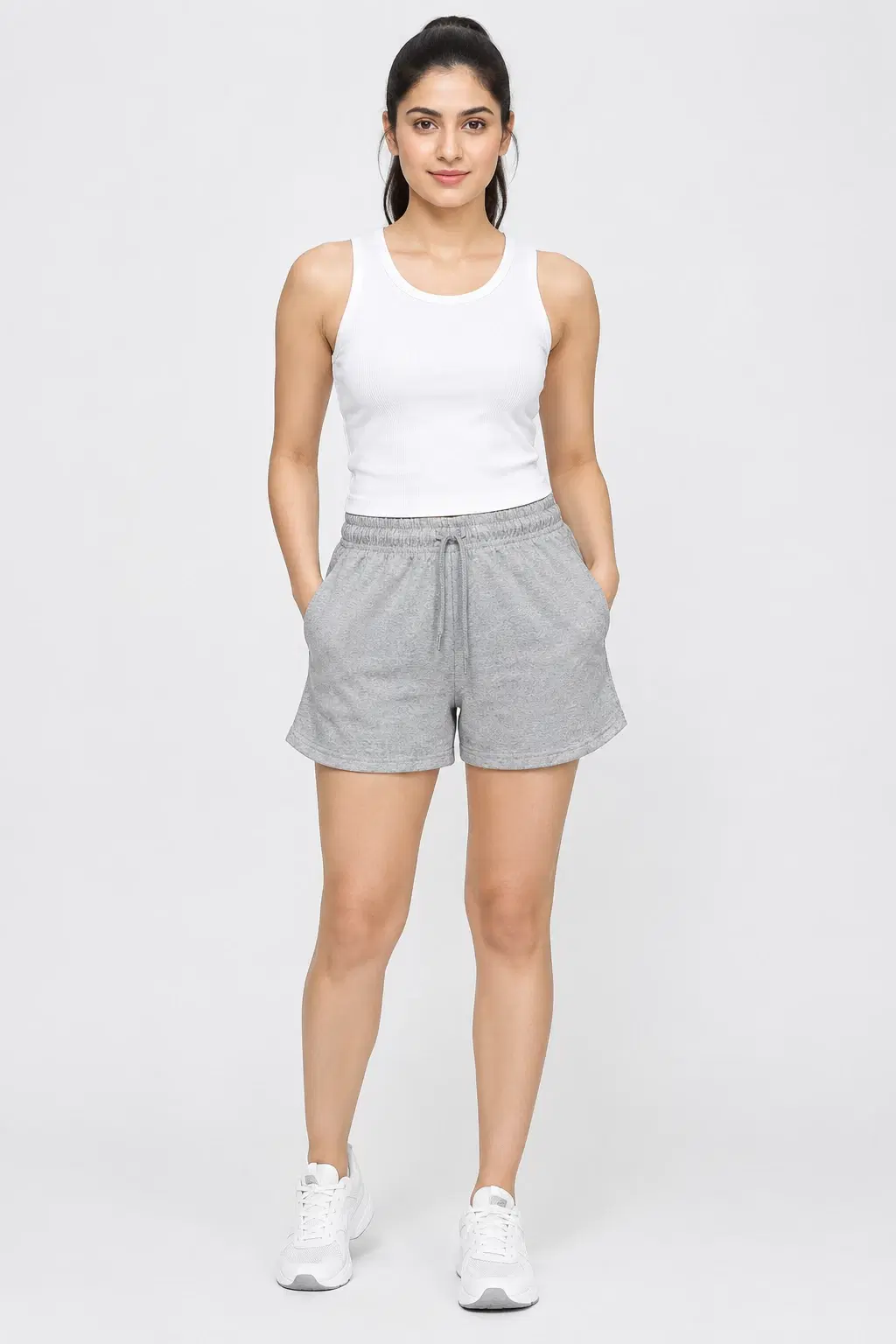Front full-length view of grey melange drawstring shorts with side pockets, styled with a white tank and sneakers