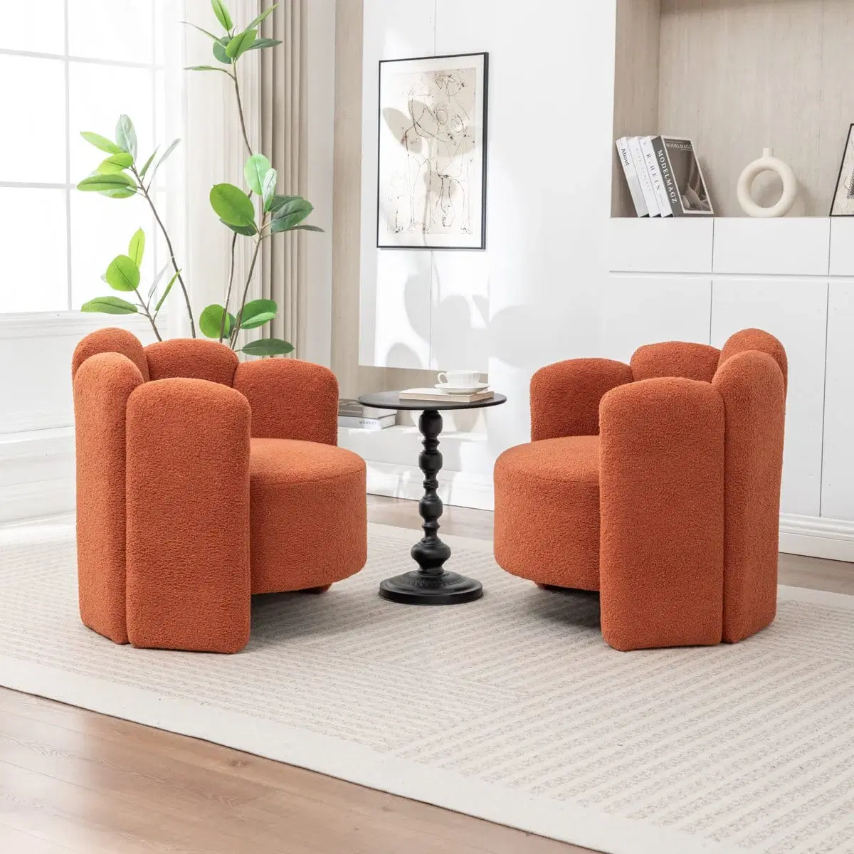 Two rust orange boucle barrel chairs styled in a living room beside a small black pedestal side table