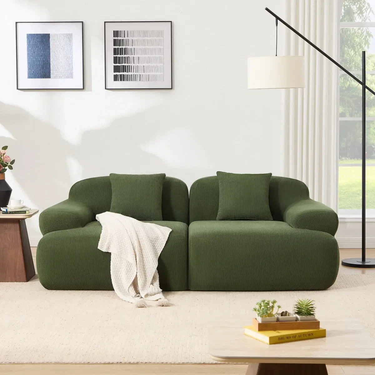 Front view of olive green modular sofa with rounded arms, two back cushions and a cream throw
