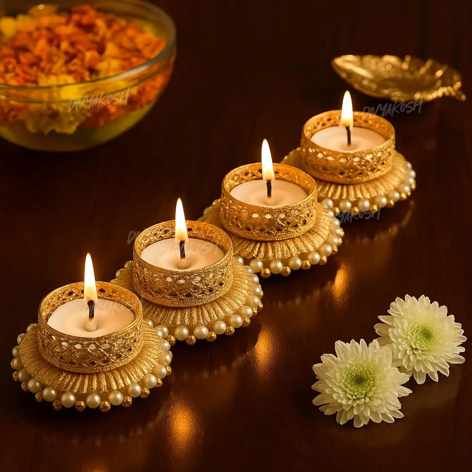 Four lit gold tealight holders with pearl-beaded bases arranged diagonally on a wooden table