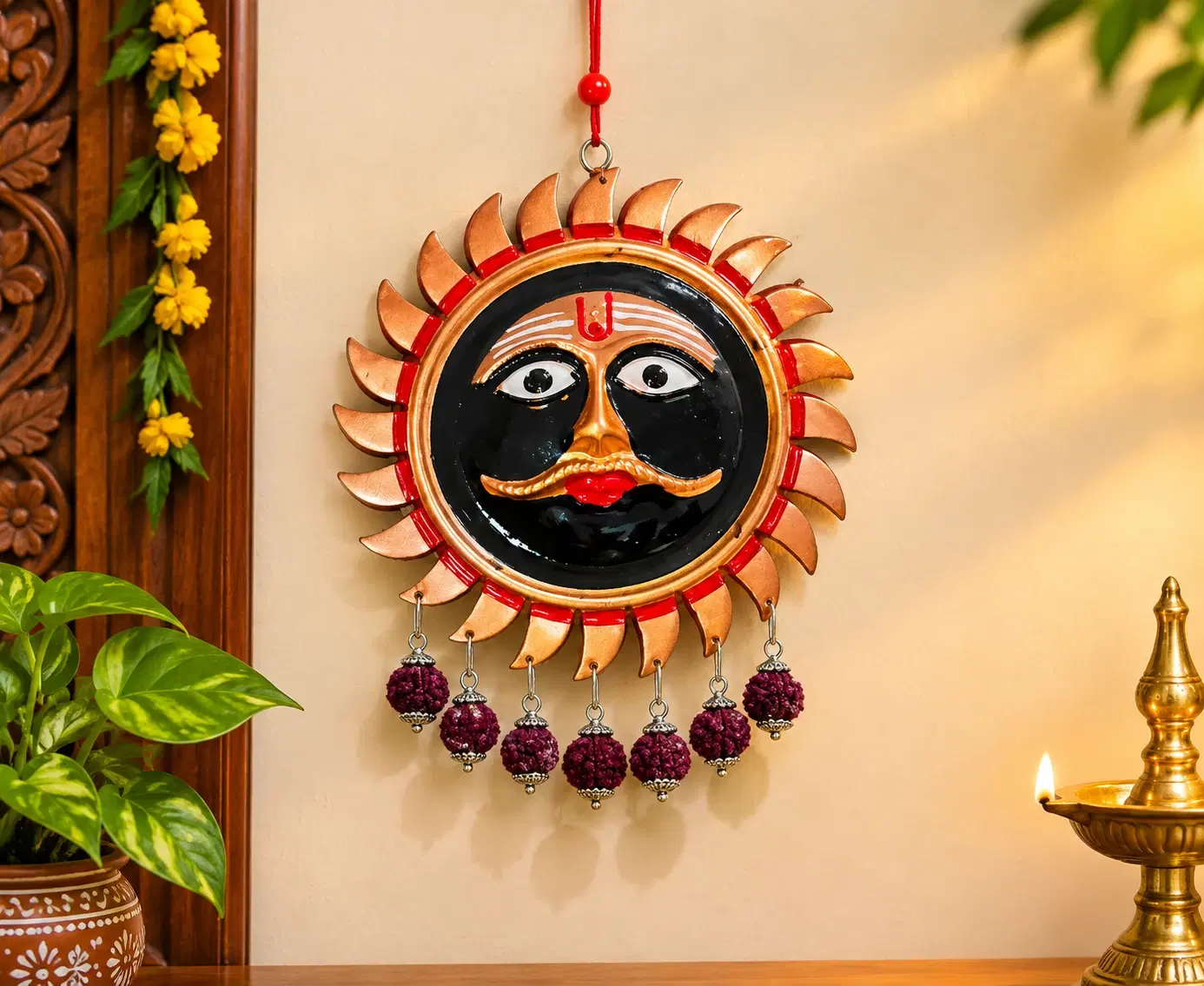 Black and gold sun face wall hanging with red accents and dangling rudraksha bead tassels on display