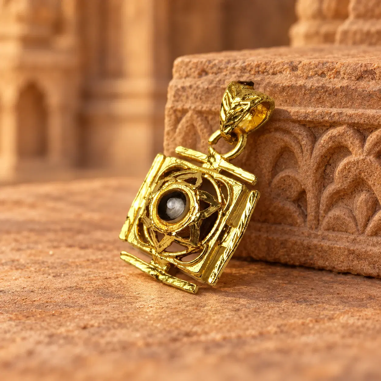 Gold pendant with circular black stone centerpiece posed against a sandstone carved backdrop