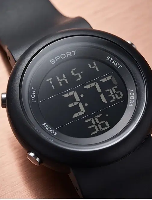 Close-up angled view of a black round digital sport watch with silicone strap and side buttons