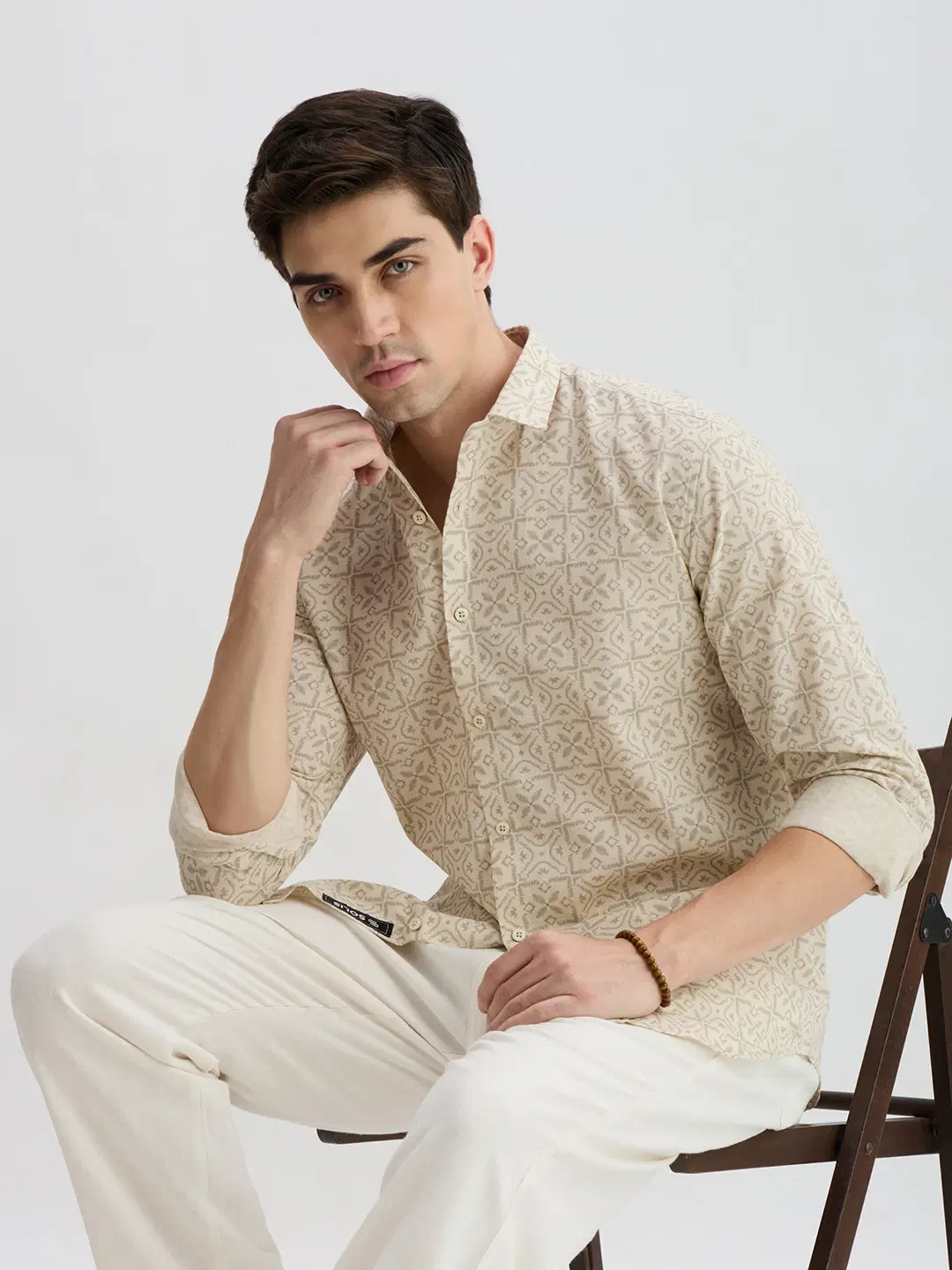 Closer seated view of the shirt highlighting front placket, rolled cuffs, and print pattern