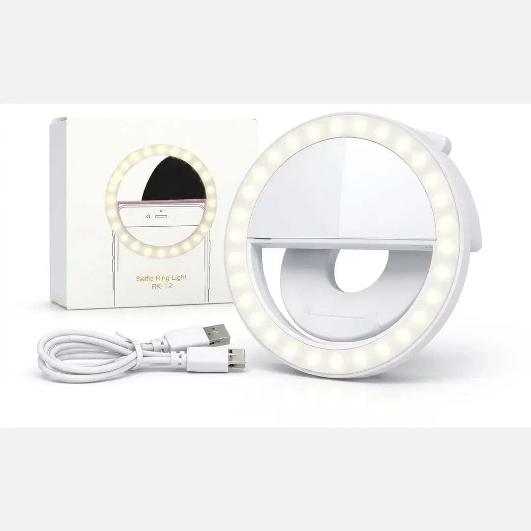 White clip-on selfie ring light with USB cable and retail box, LEDs lit on a plain background