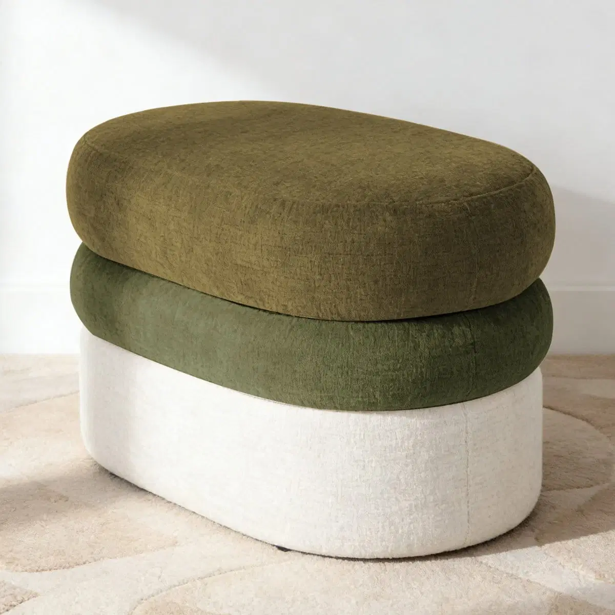 Angled studio view of oval ottoman with olive top, dark green middle band, and ivory base