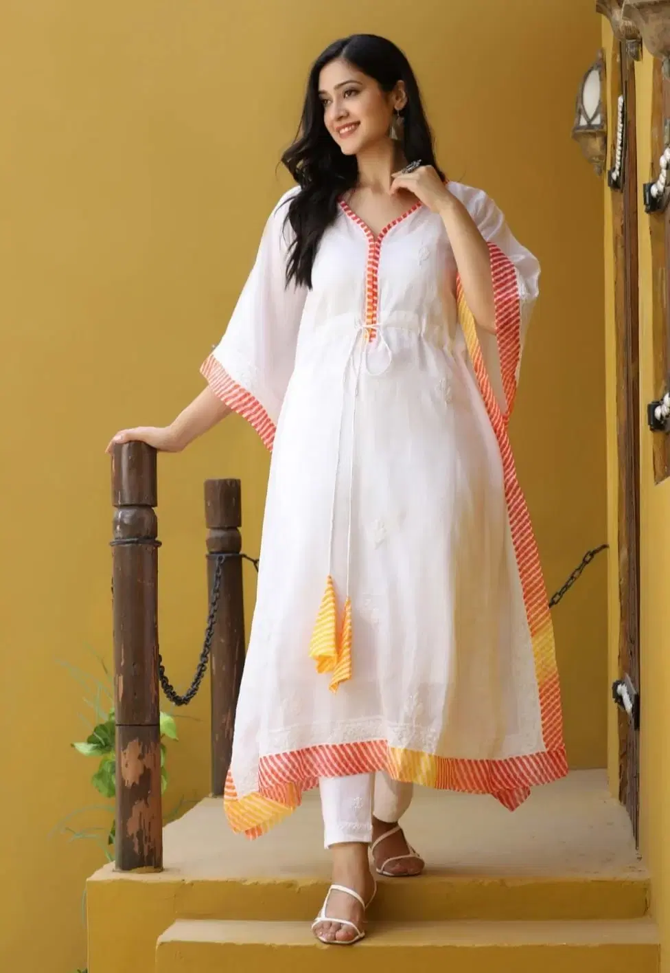 Front angled view of white kaftan kurta with drawstring waist and orange-yellow striped hem and sleeve trim