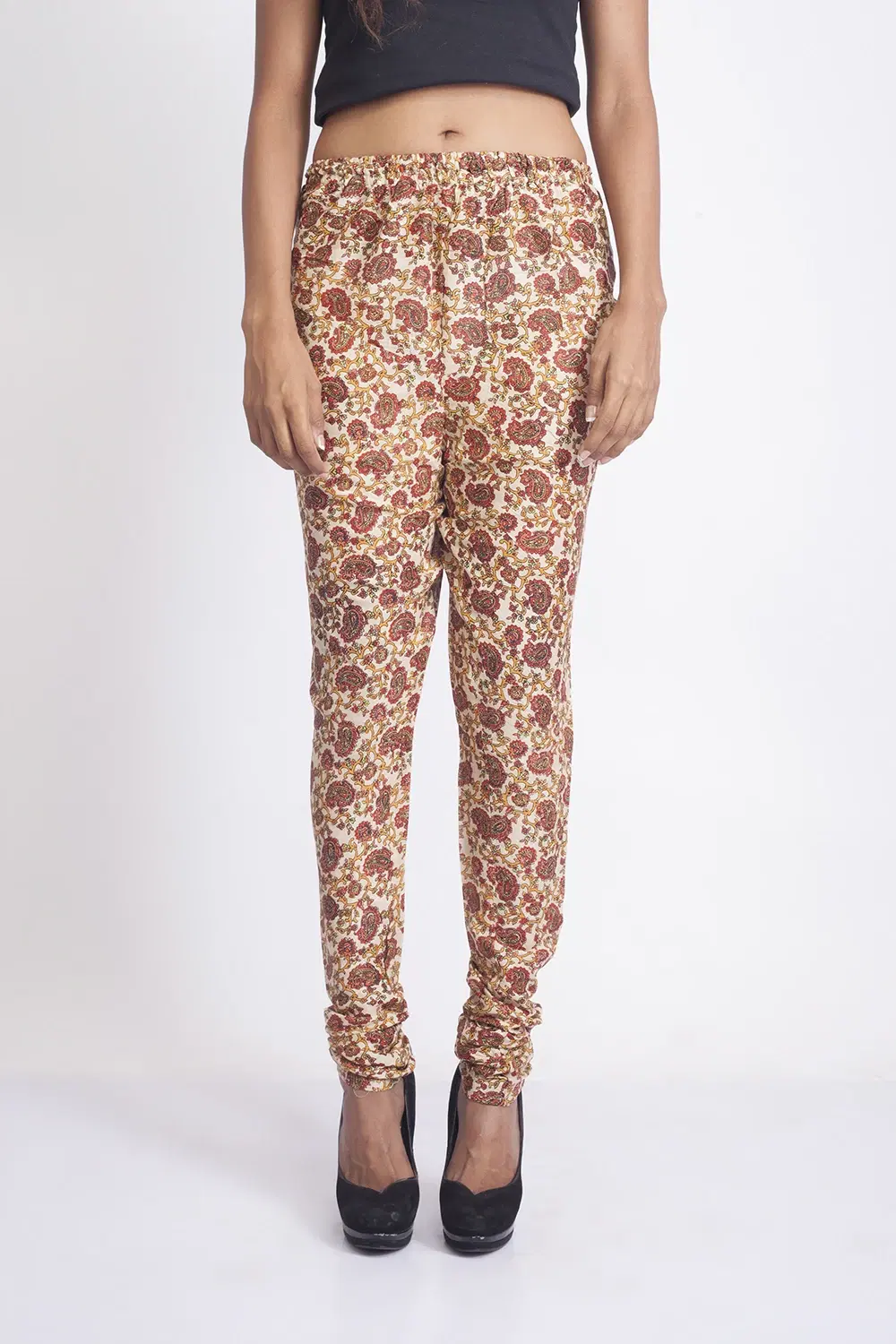 Front view of cream slim-fit leggings with red and mustard paisley print and elastic waistband