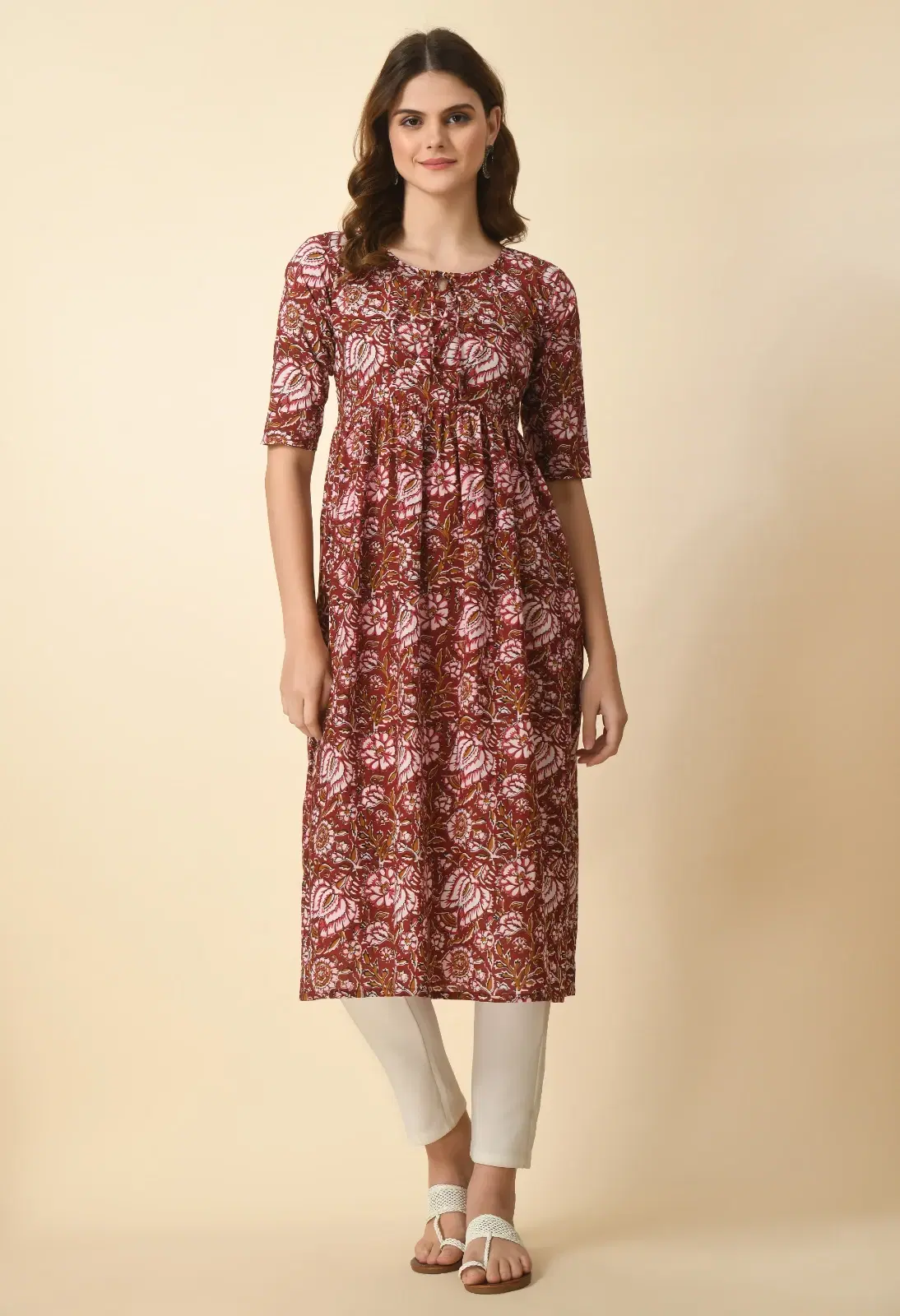 Front full-length view of a rust floral printed Anarkali kurta with 3/4 sleeves and round tie-up neckline