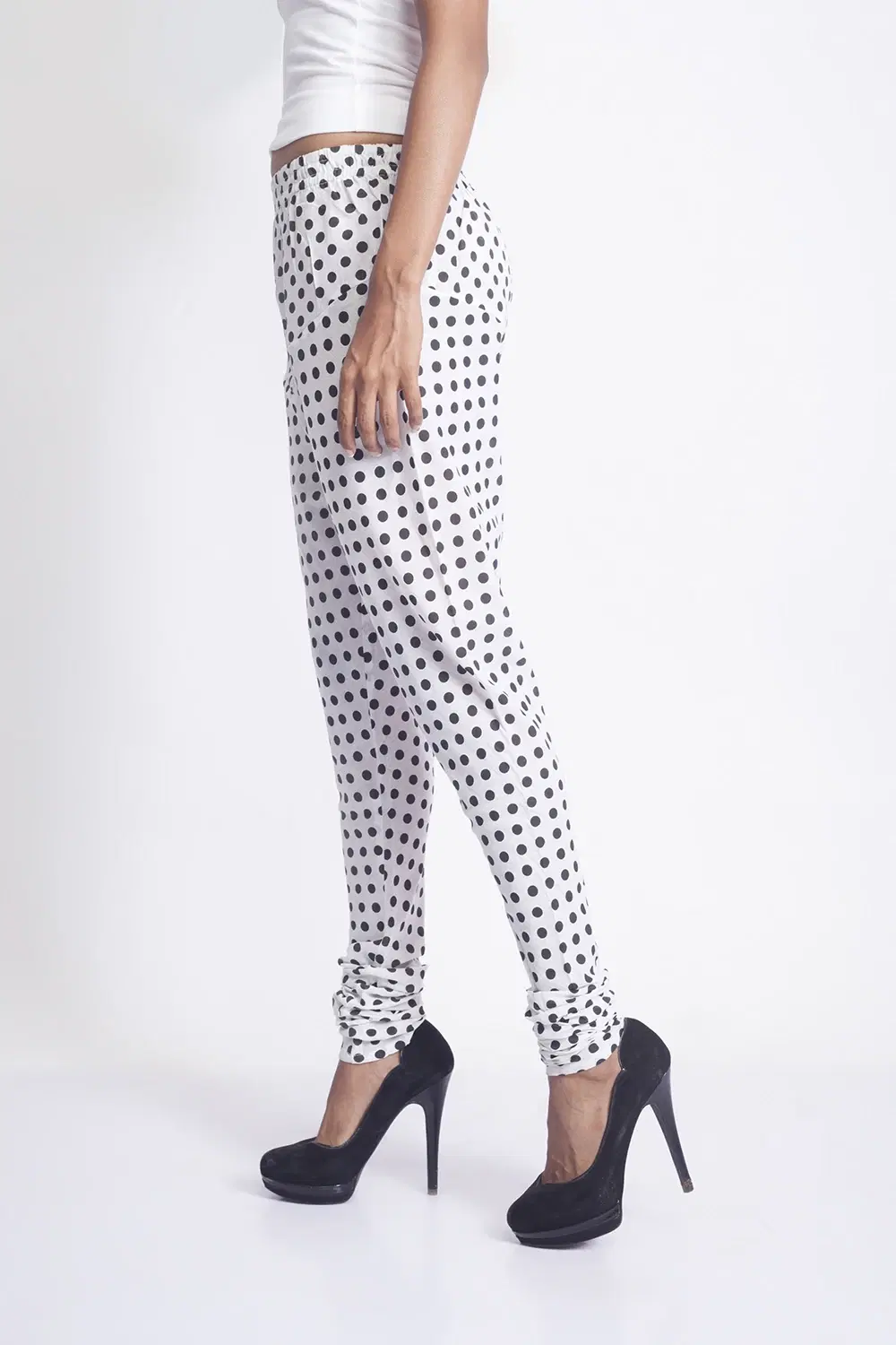 Side view of white leggings with black polka dots, shown full length with ruched ankles