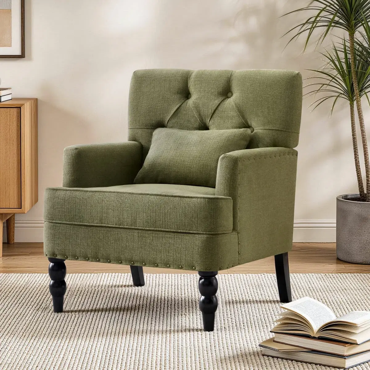 Olive green upholstered armchair with tufted back, lumbar pillow and black turned legs in a living room