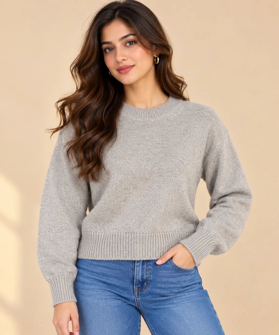 Front view of a grey crew neck knit sweater with long sleeves and ribbed hem, styled with blue jeans