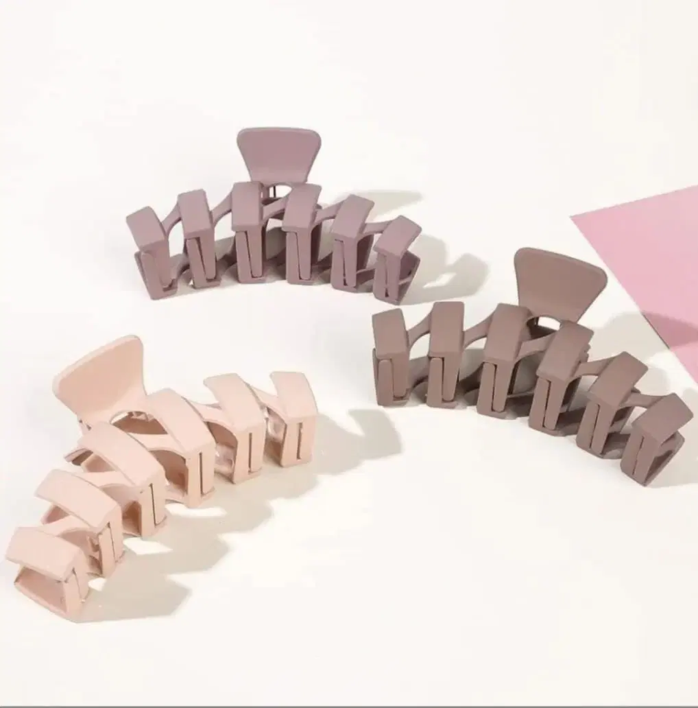 Pack of four matte jumbo hair claw clips in cream, beige and brown shades.