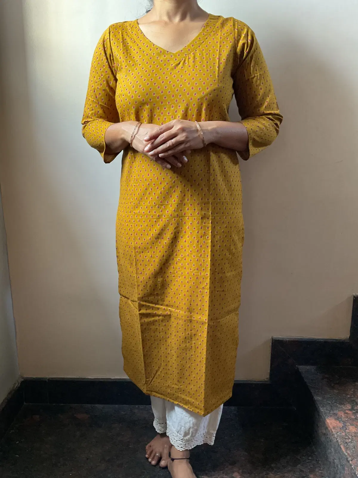 Woman wearing a mustard printed straight kurta with V-neck and three-quarter sleeves