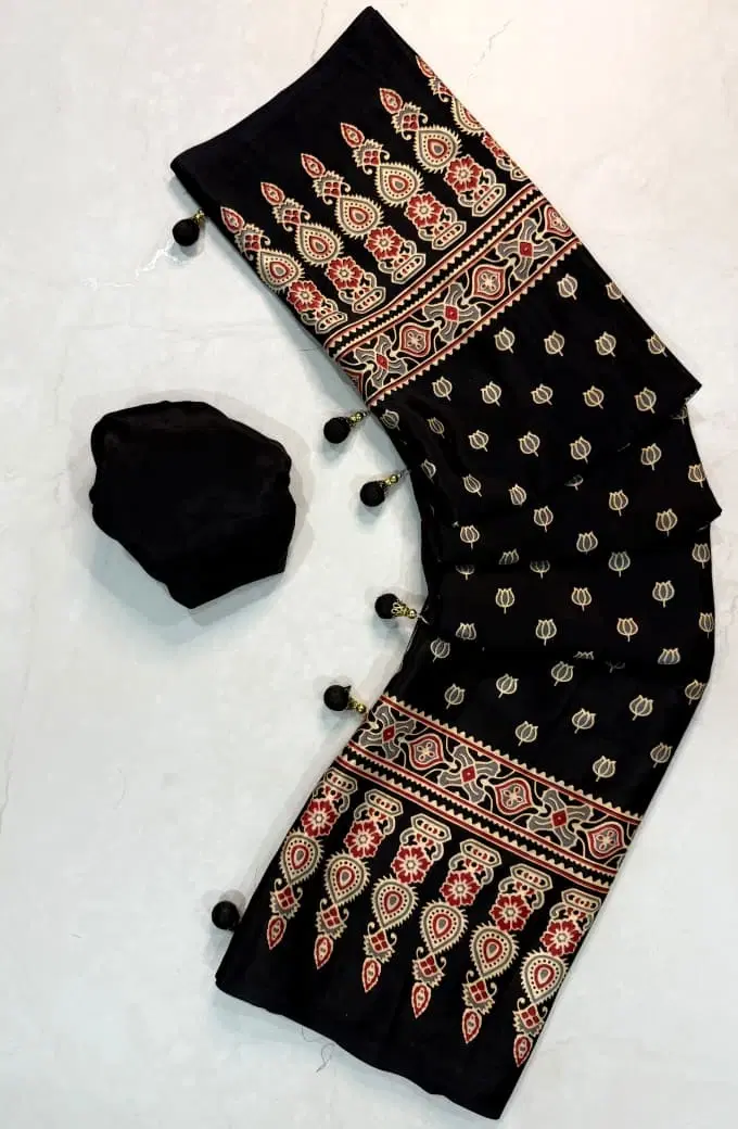 Black printed saree with red-beige border motifs, tassel accents, and matching blouse piece