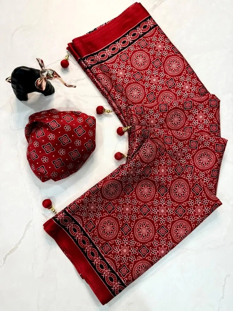 Red printed saree with tassel border and matching blouse piece laid flat on a white surface