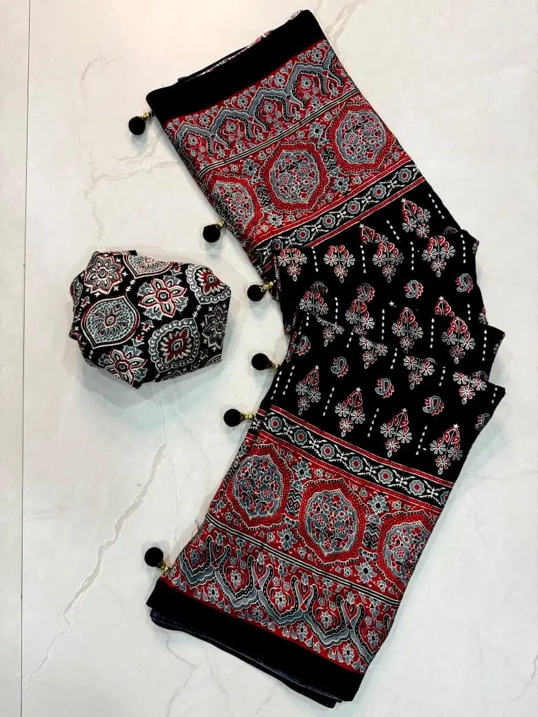 Black printed saree with red and grey traditional motifs, tassels, and matching fabric piece