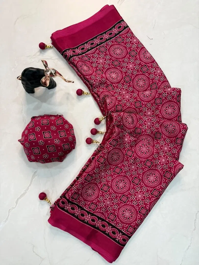 Pink printed saree with black border and tassel details, displayed with matching potli pouch