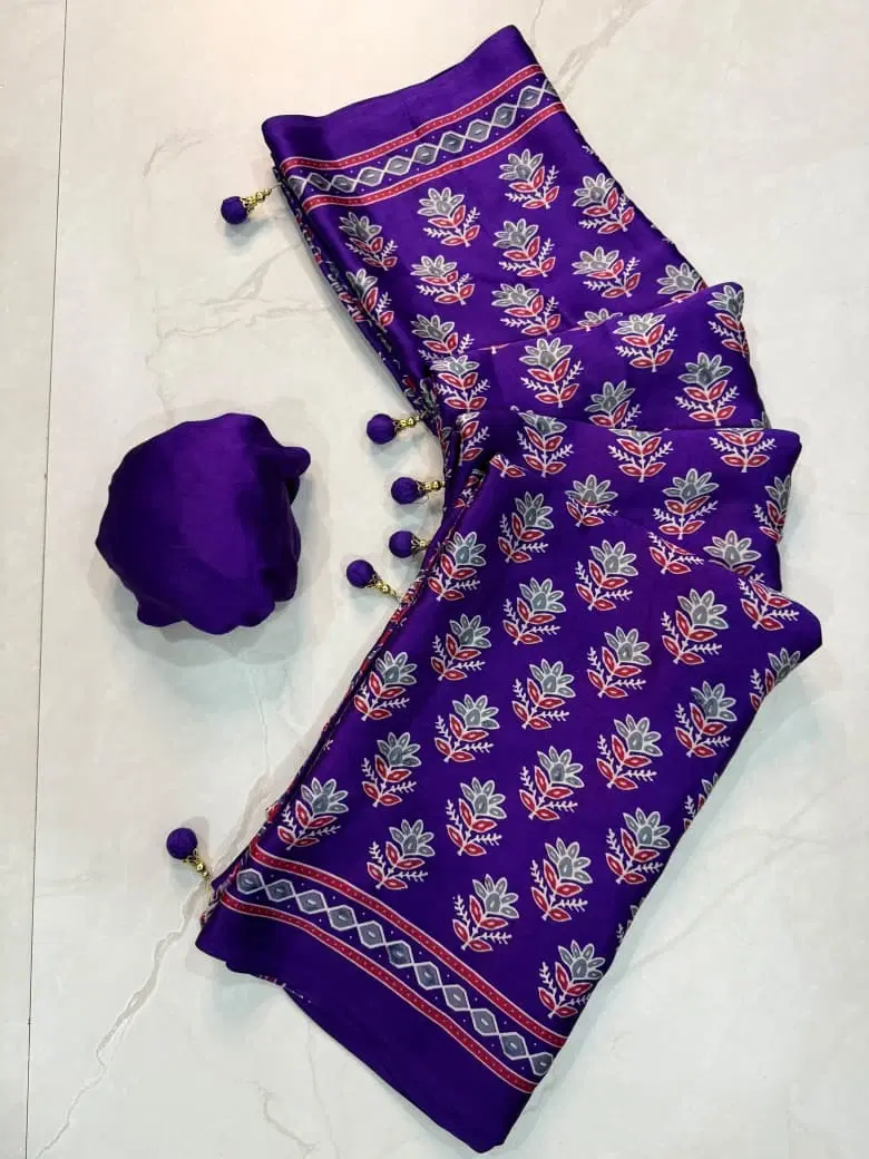 Purple printed saree with floral motifs and tassel border laid out on a light floor